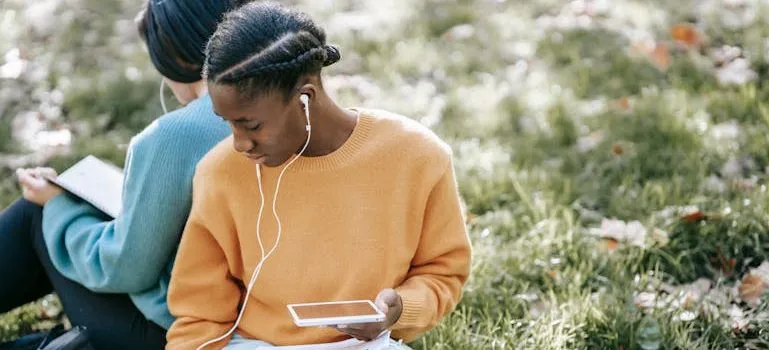 women using tablet and reading in park