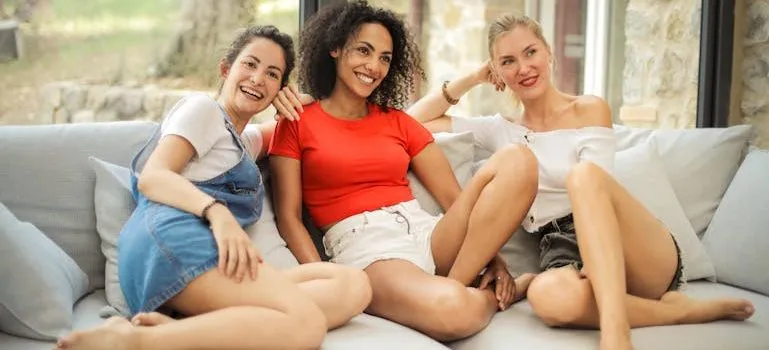 Three Laughing Woman Sitting on White Couch