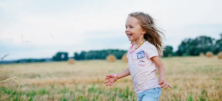 Smiling Girl Running Towards Left on Green Field
