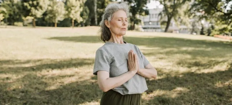 An Elderly Woman in Gray Shirt Meditating at the Park