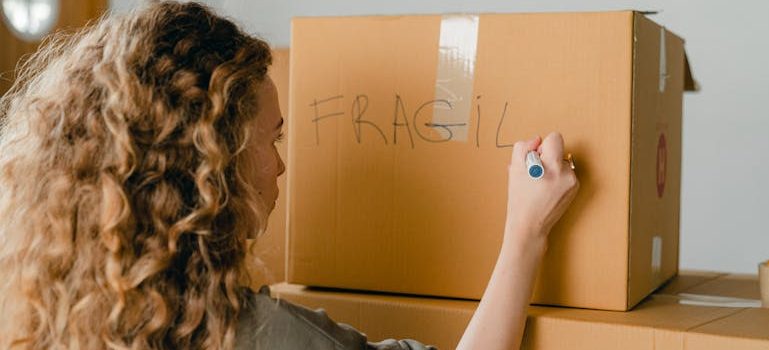 woman writing note on carton box with marker