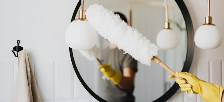 woman dusting lamp during housework