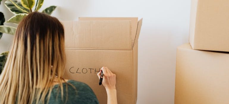 Woman packing stuff and writing on carton box