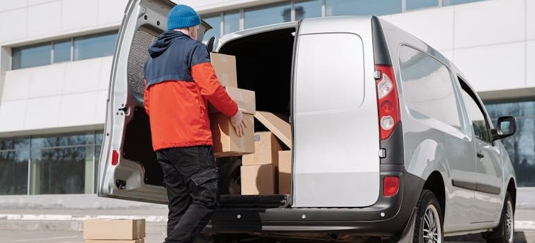 A Man in a Jacket Loading Boxes in a Van