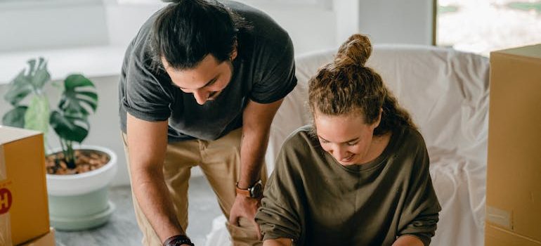 couple writing in notebook near boxes before relocation