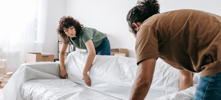 Couple Wrapping A Couch With White Cloth