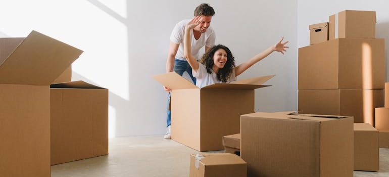 Man in White Shirt Standing Behind a Woman Sitting Inside a Box