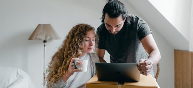Focused couple browsing laptop on cardboard box